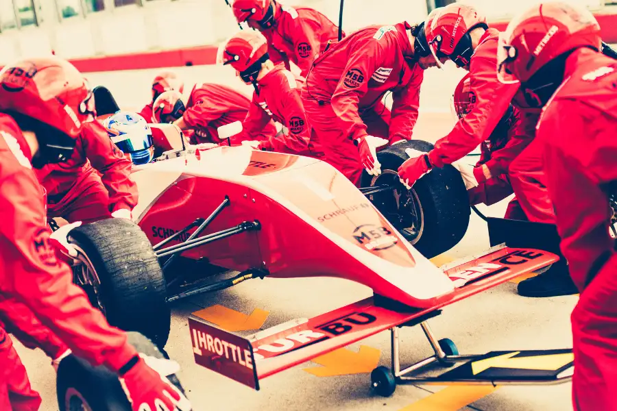 Equipe de formula 1 faz troca de pneus do veículo de alta perfomance vermelho.